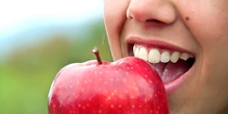 Closeup of patient with dental implants in Marietta eating an apple