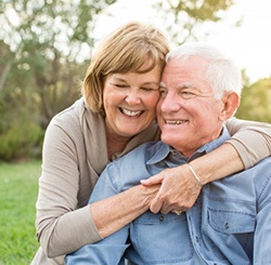 An older couple hugging and smiling outside.