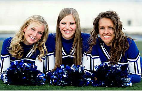 Three cheerleaders smiling outdoors