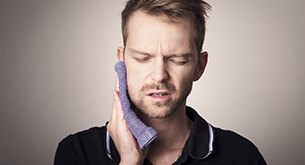 Man with tooth pain holding rag to cheek