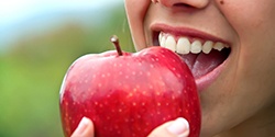 Patient with dental implants in Marietta eating an apple