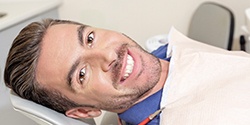 Bearded man lying back and smiling while visiting oral surgeon
