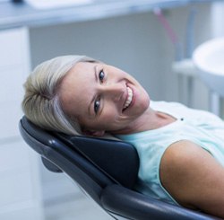Woman leaning back and smiling in chair at oral surgeon’s office