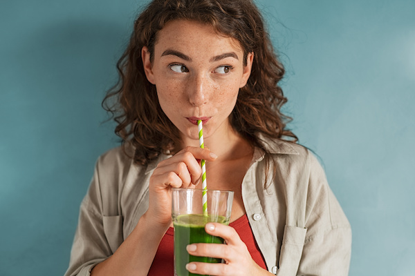 woman drinking through straw looking off to the side
